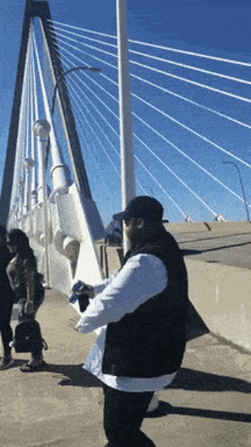 a man standing in front of a bridge holding a bottle