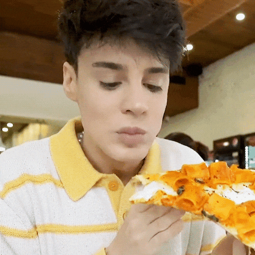 a young man is eating a large slice of pizza