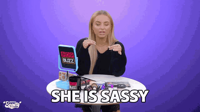 a woman sitting at a table with a mirror and a cup that says " she is sassy "