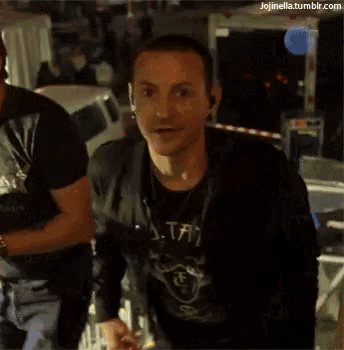 a man wearing a black shirt with the letter t on it is smiling