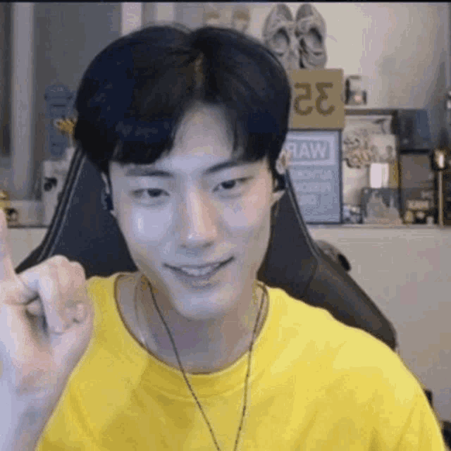 a young man wearing a yellow t-shirt is sitting in a chair and smiling .