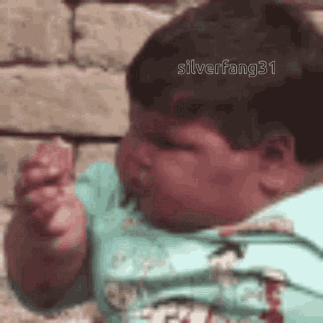 a baby is eating a piece of food and making a face .