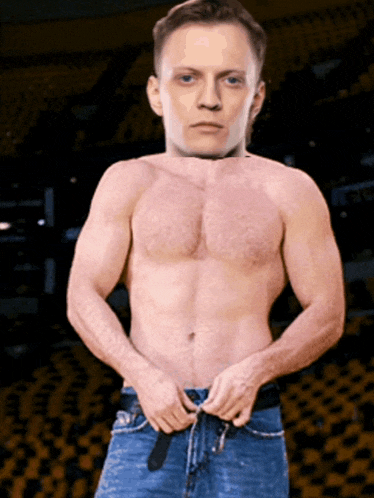 a shirtless man is adjusting his jeans in front of a crowd