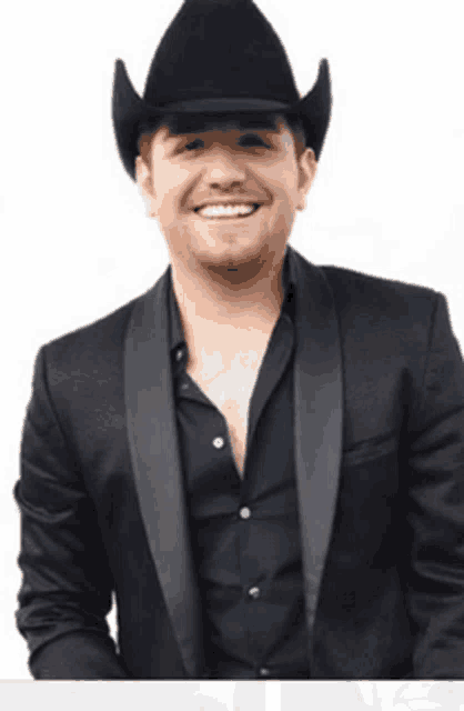 a man wearing a cowboy hat and a tuxedo is smiling