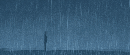 a man is standing in the rain on a hill .