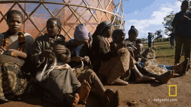 a group of people are sitting on the ground with natgeotv.com written on the bottom