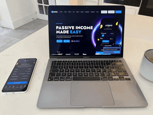 a laptop and a phone on a counter with the website passive income made easy on the screen