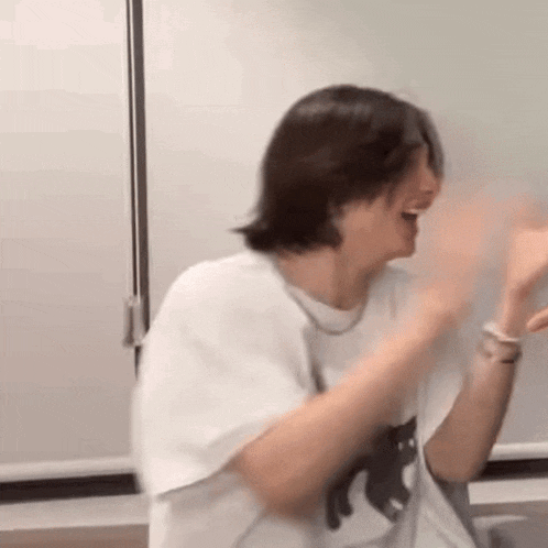 a man in a white shirt is laughing and waving his hands .