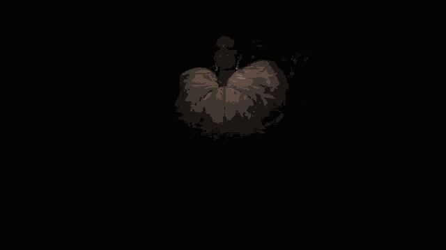 a woman in a white dress sitting in a dark room
