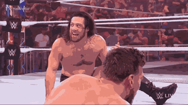 two wrestlers in a wrestling ring with a w logo on the side