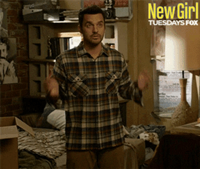 a man in a plaid shirt is standing in front of a sign that says new girl tuesdays