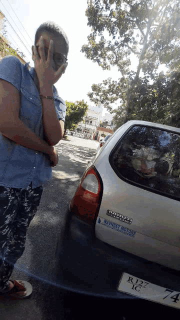 a man talking on a cell phone in front of a car that says naveet motors