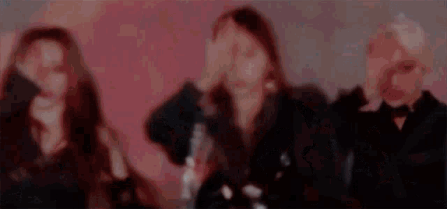 a group of women are dancing in a dark room with a red background .