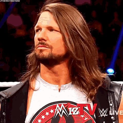 a man with long hair and a beard is wearing a shirt that says miz tv on it .