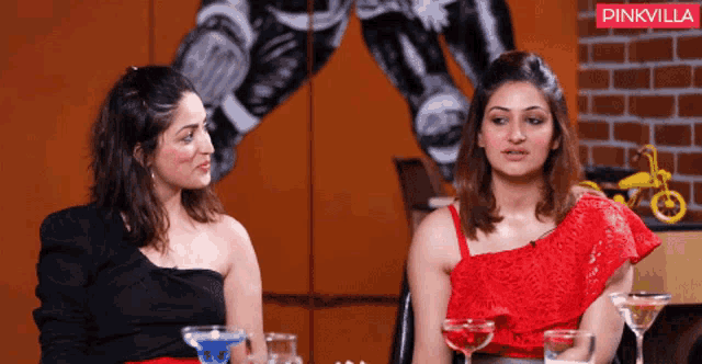 two women sitting next to each other in front of a pinkvilla sign