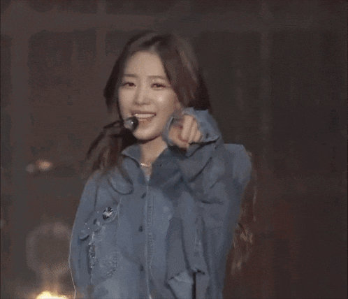 a woman wearing a blue shirt and a microphone is smiling .