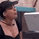 a woman wearing a baseball cap and a black top is standing in front of a computer .