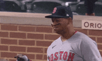 a baseball player wearing a boston red sox jersey is standing in the dugout .