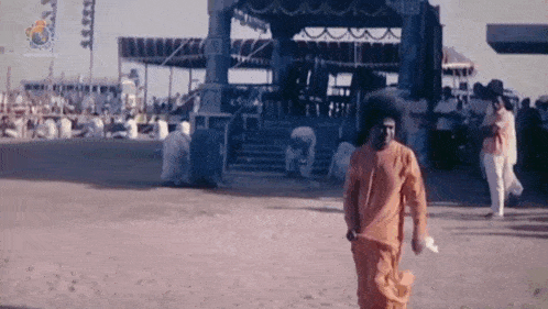 a man in an orange robe is walking in a crowded area