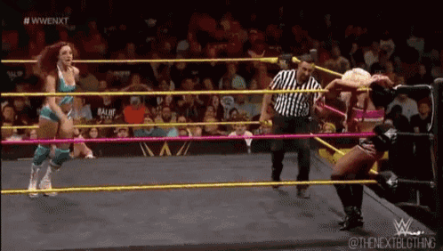 two women are wrestling in a ring while a referee watches