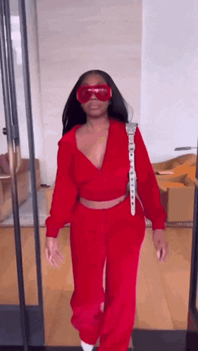 a woman in a red outfit and red goggles is standing in a room .