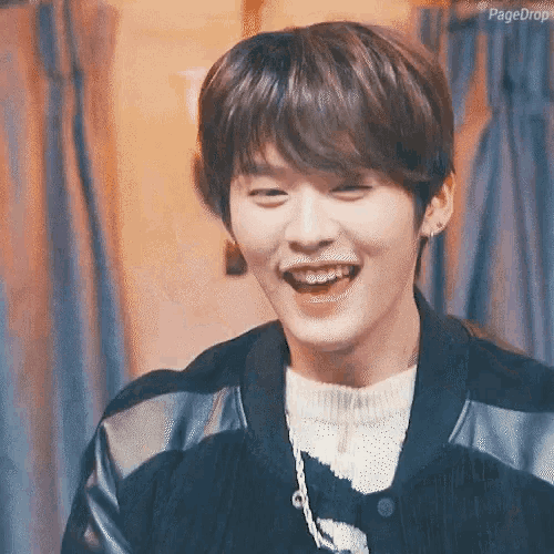 a young man with braces on his teeth is smiling while wearing a black jacket .