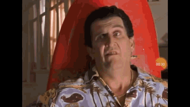 a man is sitting in a chair with a red surfboard in the background and a yellow circle that says 00:00 on it