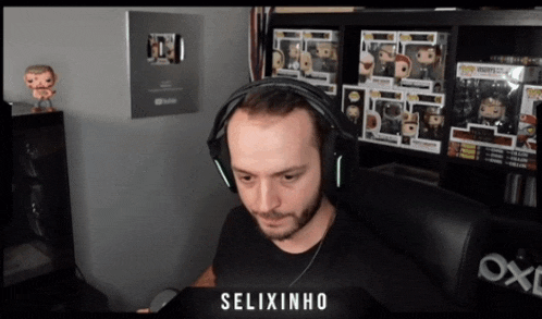 a man wearing headphones is sitting in front of a shelf of funko pop figures