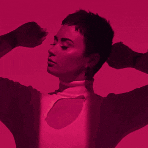 a woman wearing a turtleneck sweater has her eyes closed and her hands behind her head