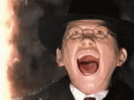 a man in a top hat and glasses is laughing with his mouth open .