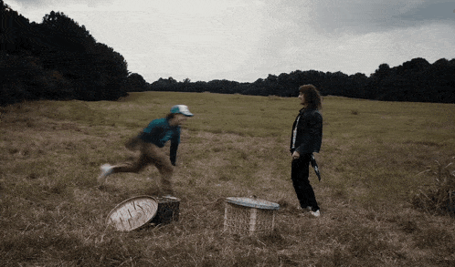 a man and a woman are playing in a field and the woman is wearing a black jacket