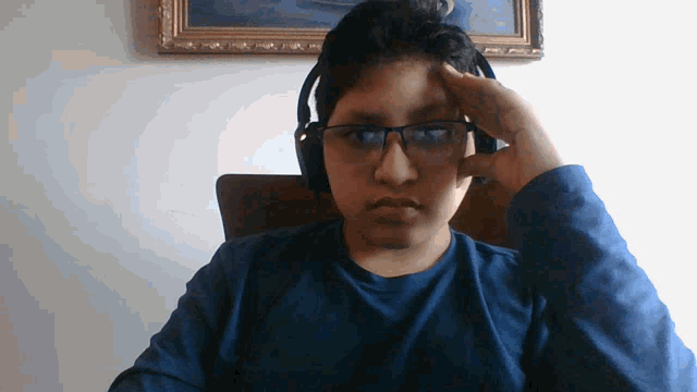 a young man wearing glasses and headphones is sitting in front of a framed picture