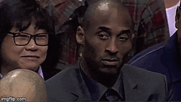 a man in a suit and tie is sitting in a stadium with a woman behind him .