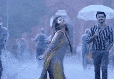 a man is holding an umbrella over a woman dancing in the rain .