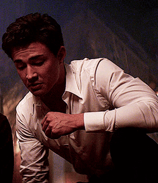a man in a white shirt is looking down