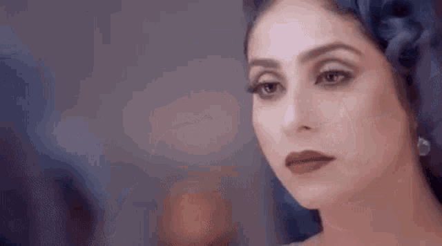 a woman is looking at herself in the mirror while wearing a head scarf .