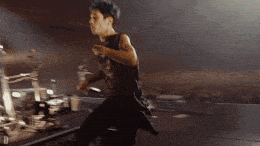 a man in a black tank top is running on a stage