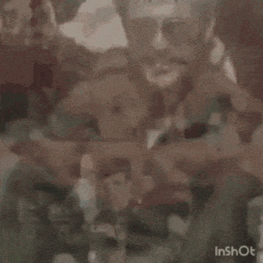 a man in a military uniform with a mustache and sunglasses is sitting down .
