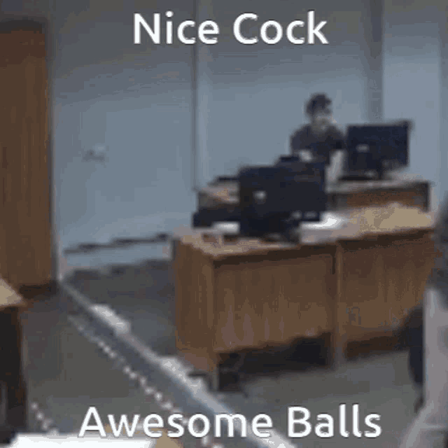 a man is sitting at a desk in an office with the words `` nice cock awesome balls '' .