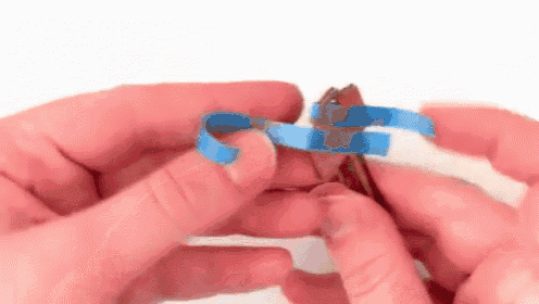 a person is holding a piece of wood and a blue tape .