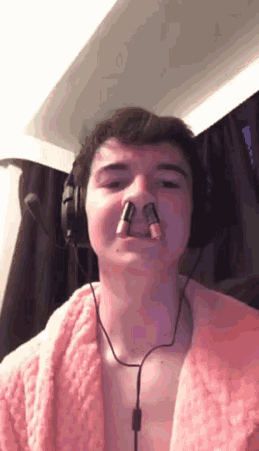 a man wearing headphones and a pink robe has lipstick in his nose