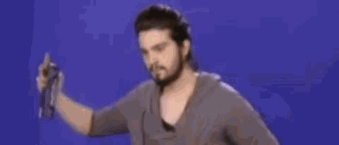 a man with a beard is holding a spray can in his hand .