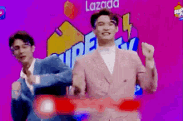 two men in suits are dancing in front of a sign that says lazada
