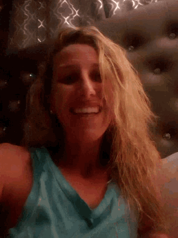 a woman in a blue shirt is smiling and looking down