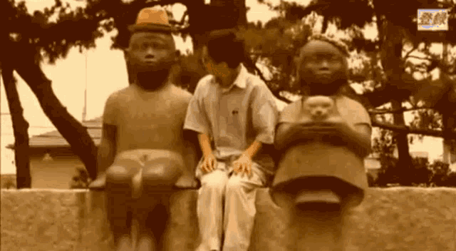 a man is sitting on a ledge between two statues of people .