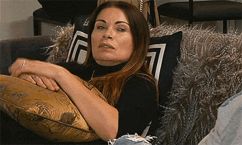 a woman is sitting on a couch with a pillow in her lap and looking at the camera .