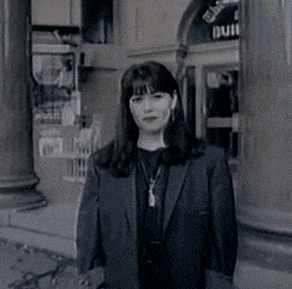 a woman in a suit stands in front of a building that has a sign that says building