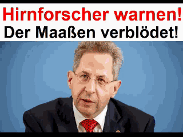 a man in a suit and tie stands in front of a banner that says hirnforscher warnen
