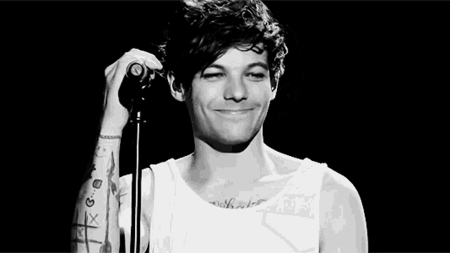 a black and white photo of a man holding a microphone .