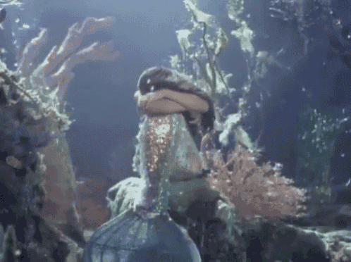 a mermaid is swimming in the ocean and covering her face